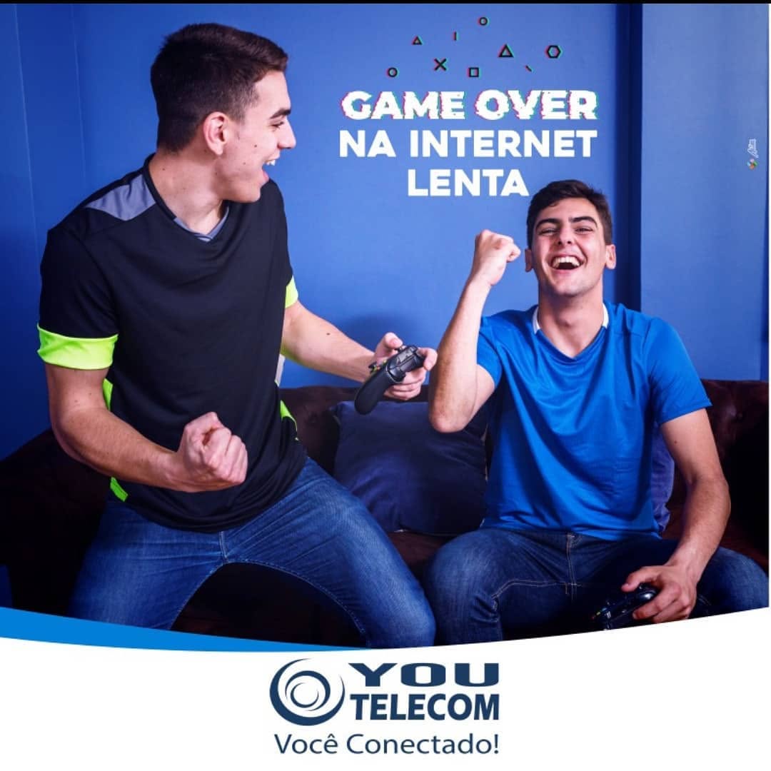 Campanha da You Telecom com dois amigos jogando videogame e a frase Game over na internet lenta.
